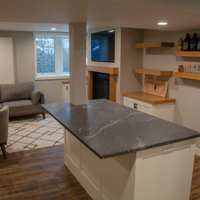 Mid-sized elegant vinyl floor and brown floor basement photo in Minneapolis with a bar, a standard fireplace and a wood fireplace surround