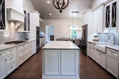 Example of a large transitional galley light wood floor eat-in kitchen design in Chicago with a farmhouse sink, flat-panel cabinets, white cabinets, quartzite countertops, gray backsplash, stone slab backsplash, stainless steel appliances and an island