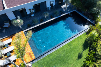 Backyard tile and rectangular pool photo in Other