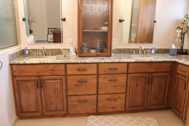 Example of a mid-sized classic master brown tile and porcelain tile porcelain tile and beige floor bathroom design in Phoenix with raised-panel cabinets, medium tone wood cabinets, beige walls, an undermount sink and granite countertops