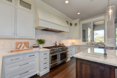 Example of a large transitional dark wood floor and brown floor kitchen design in Sacramento with an undermount sink, shaker cabinets, white cabinets, white backsplash, marble backsplash, stainless steel appliances, an island and white countertops