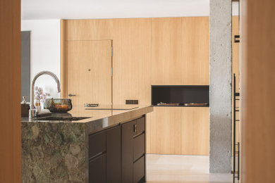 Cette image montre une cuisine ouverte minimaliste de taille moyenne avec un placard à porte plane, des portes de placard noires, plan de travail en marbre, un sol en calcaire, îlot, un sol marron et un plan de travail vert.