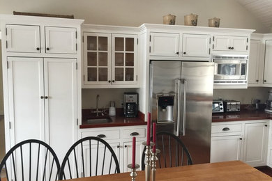 Mid-sized trendy l-shaped dark wood floor and brown floor eat-in kitchen photo in Boston with an undermount sink, shaker cabinets, white cabinets, solid surface countertops, red backsplash, stainless steel appliances, stone slab backsplash and no island