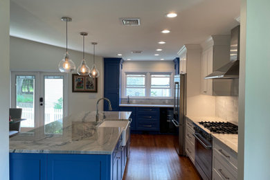 Eat-in kitchen - mid-sized 1960s u-shaped medium tone wood floor, brown floor and vaulted ceiling eat-in kitchen idea in New York with a farmhouse sink, shaker cabinets, blue cabinets, quartzite countertops, white backsplash, ceramic backsplash, stainless steel appliances, an island and gray countertops