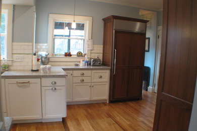 Mid-sized elegant single-wall light wood floor enclosed kitchen photo in Other with shaker cabinets, white cabinets, granite countertops, white backsplash, subway tile backsplash, paneled appliances and an undermount sink