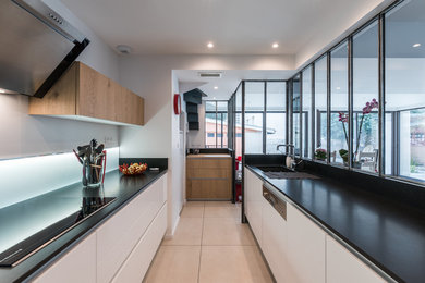 Design ideas for a large contemporary galley kitchen in Lyon with a single-bowl sink, white cabinets, granite benchtops, white splashback, glass sheet splashback, stainless steel appliances, ceramic floors and no island.