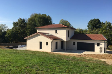 Aménagement d'une façade de maison beige classique de taille moyenne et à un étage avec un toit à quatre pans.