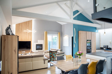 Idée de décoration pour un salon design de taille moyenne et ouvert avec un mur marron, parquet clair, une cheminée standard, un manteau de cheminée en pierre de parement, un téléviseur fixé au mur, un sol marron et poutres apparentes.
