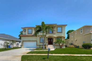 Mid-sized traditional beige two-story stucco house exterior idea in Tampa with a hip roof