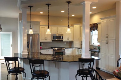Mid-sized transitional u-shaped dark wood floor and brown floor enclosed kitchen photo in Baltimore with a double-bowl sink, raised-panel cabinets, white cabinets, granite countertops, white backsplash, subway tile backsplash, stainless steel appliances and a peninsula