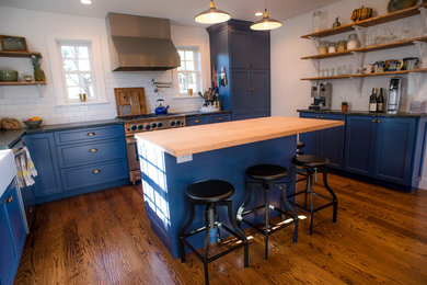 Inspiration for a mid-sized country l-shaped kitchen in Philadelphia with shaker cabinets, blue cabinets, soapstone benchtops, white splashback, ceramic splashback, stainless steel appliances, medium hardwood floors and with island.