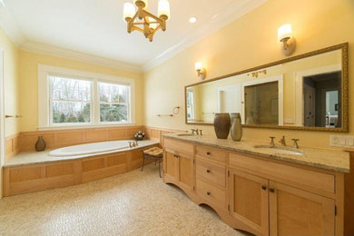 Drop-in bathtub - large transitional master beige tile ceramic tile drop-in bathtub idea in New York with medium tone wood cabinets, a one-piece toilet, yellow walls, a drop-in sink, granite countertops and shaker cabinets