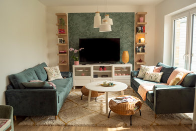 Mittelgroßes, Offenes Skandinavisches Wohnzimmer mit grüner Wandfarbe, TV-Wand, braunem Boden und hellem Holzboden in Sonstige