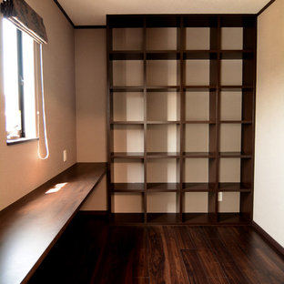 Photo of a modern study in Other with white walls, plywood flooring, a built-in desk and brown floors.