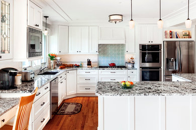 Eat-in kitchen - large transitional l-shaped medium tone wood floor and brown floor eat-in kitchen idea in Wiltshire with an undermount sink, shaker cabinets, white cabinets, glass countertops, blue backsplash, ceramic backsplash, stainless steel appliances and an island