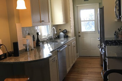 Example of a small transitional galley light wood floor enclosed kitchen design in Philadelphia with an undermount sink, flat-panel cabinets, yellow cabinets, quartz countertops, white backsplash, ceramic backsplash, stainless steel appliances and no island