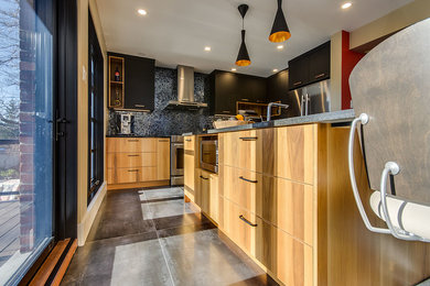 Large contemporary l-shaped eat-in kitchen in Montreal with a single-bowl sink, flat-panel cabinets, granite benchtops, grey splashback, glass tile splashback, stainless steel appliances, porcelain floors, with island, brown floor and light wood cabinets.