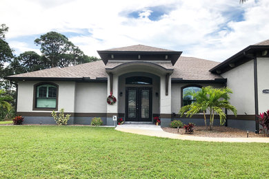 Inspiration for a mediterranean one-story stucco house exterior remodel in Tampa with a hip roof and a shingle roof
