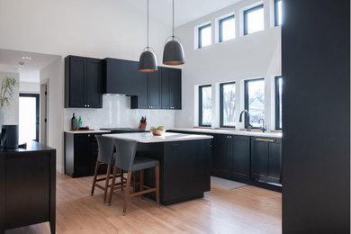 Eat-in kitchen - mid-sized transitional u-shaped light wood floor, beige floor and vaulted ceiling eat-in kitchen idea in Chicago with an undermount sink, shaker cabinets, black cabinets, quartz countertops, white backsplash, quartz backsplash, paneled appliances, an island and white countertops