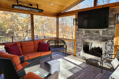 Inspiration for a mid-sized rustic mixed material railing back porch remodel in Kansas City with a fireplace and a roof extension