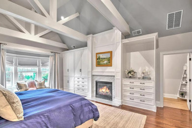 ブリッジポートにある広いコンテンポラリースタイルのおしゃれな主寝室 (無垢フローリング、横長型暖炉、木材の暖炉まわり、茶色い床、羽目板の壁、板張り壁) のレイアウト