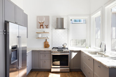 Kitchen - transitional u-shaped medium tone wood floor and brown floor kitchen idea in Other with a double-bowl sink, shaker cabinets, gray cabinets, white backsplash, subway tile backsplash, stainless steel appliances, marble countertops and white countertops
