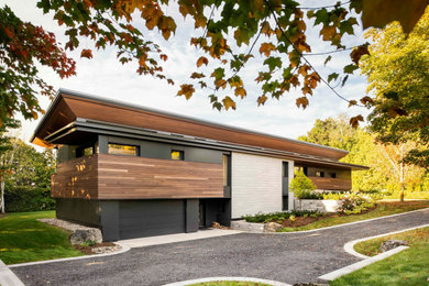 Large 1950s black two-story mixed siding and board and batten house exterior photo in Toronto with a shed roof, a metal roof and a black roof