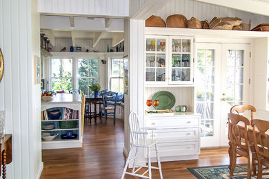 Enclosed kitchen - mid-sized coastal l-shaped medium tone wood floor enclosed kitchen idea in Jacksonville with beaded inset cabinets, white cabinets, solid surface countertops, paneled appliances, an island and white countertops