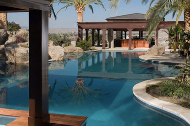 This is an example of a tropical backyard custom-shaped pool in San Diego with a pool house.