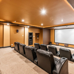 Photo of a traditional enclosed home cinema in Other with orange walls, carpet, a projector screen and beige floors.