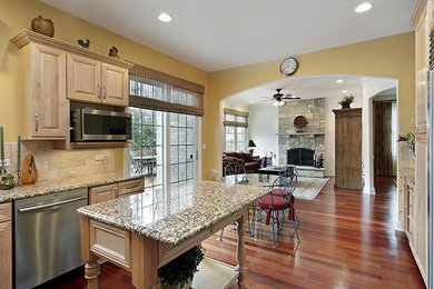 Mid-sized minimalist u-shaped medium tone wood floor and brown floor kitchen photo in Chicago with beaded inset cabinets, light wood cabinets, granite countertops, beige backsplash, porcelain backsplash, stainless steel appliances, an island and multicolored countertops