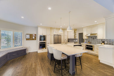 Example of a large transitional l-shaped dark wood floor and brown floor eat-in kitchen design in Denver with an undermount sink, shaker cabinets, white cabinets, quartz countertops, blue backsplash, ceramic backsplash, black appliances, two islands and white countertops