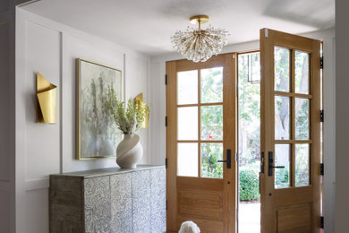 Imagen de distribuidor clásico renovado con paredes blancas, suelo de madera en tonos medios, puerta doble, puerta de madera en tonos medios y suelo marrón