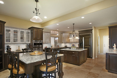Inspiration for a huge timeless l-shaped travertine floor eat-in kitchen remodel in Phoenix with an undermount sink, raised-panel cabinets, dark wood cabinets, granite countertops, white backsplash, ceramic backsplash, stainless steel appliances and two islands