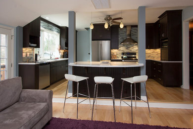 Large trendy u-shaped light wood floor and yellow floor open concept kitchen photo in Raleigh with a single-bowl sink, flat-panel cabinets, dark wood cabinets, quartz countertops, multicolored backsplash, glass tile backsplash, stainless steel appliances, an island and white countertops