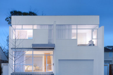 Example of a minimalist white two-story flat roof design in Houston