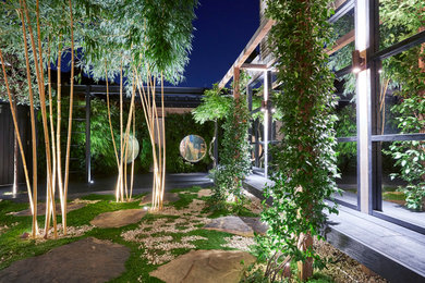 Photo of a mid-sized asian courtyard partial sun formal garden in London with a vertical garden and gravel.