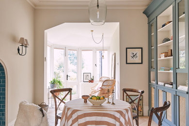 Exemple d'une salle à manger ouverte sur le salon éclectique de taille moyenne avec un mur blanc, parquet clair, aucune cheminée, un manteau de cheminée en carrelage et un sol gris.