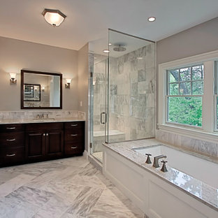 Idée de décoration pour une salle de bain tradition de taille moyenne avec un mur gris, un placard avec porte à panneau surélevé, des portes de placard en bois sombre, une baignoire encastrée, une douche d'angle, un carrelage gris, du carrelage en marbre, un sol en marbre, un lavabo encastré, un plan de toilette en marbre, un sol gris et une cabine de douche à porte battante.