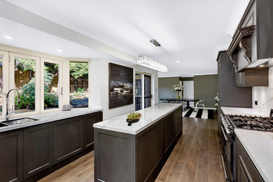 Inspiration for a midcentury galley open plan kitchen in Central Coast with a single-bowl sink, glass-front cabinets, dark wood cabinets, quartzite benchtops, white splashback, stone slab splashback, black appliances, vinyl floors and with island.
