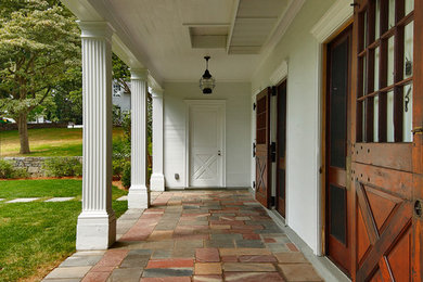 Design ideas for a mid-sized country front yard verandah in New York with natural stone pavers and a roof extension.
