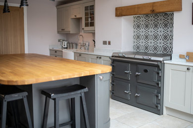 Photo of a large traditional single-wall kitchen/diner in Other with a belfast sink, shaker cabinets, grey cabinets, wood worktops, multi-coloured splashback, porcelain splashback, stainless steel appliances, an island and white worktops.