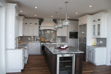 Example of a large transitional u-shaped medium tone wood floor and brown floor open concept kitchen design in Edmonton with an undermount sink, recessed-panel cabinets, white cabinets, granite countertops, gray backsplash, glass tile backsplash, stainless steel appliances and an island