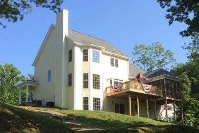 Large elegant yellow three-story exterior home photo in Other