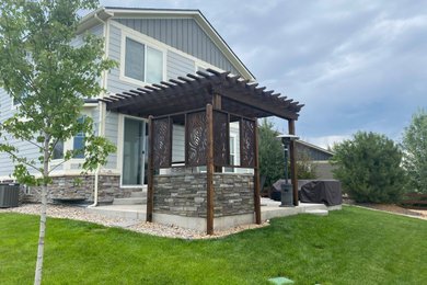 Example of a mid-sized mountain style backyard concrete patio design in Denver with a fireplace and a pergola