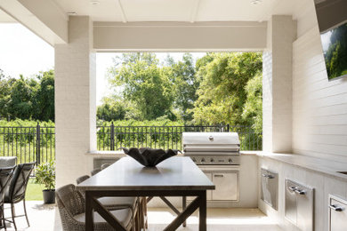 Inspiration for a transitional backyard concrete paver patio kitchen remodel in New Orleans with a roof extension