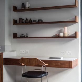 Inspiration för små moderna arbetsrum, med vita väggar, betonggolv, ett inbyggt skrivbord och grått golv