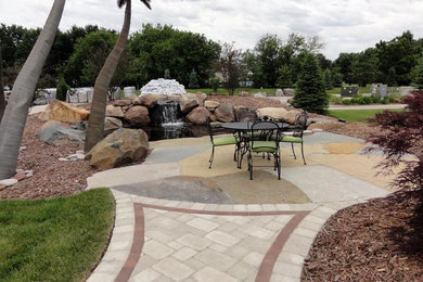This is an example of a large transitional backyard concrete paver water fountain landscape in Other.
