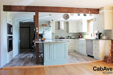 Inredning av ett lantligt mellanstort kök, med en rustik diskho, luckor med upphöjd panel, vita skåp, bänkskiva i kvarts, grönt stänkskydd, stänkskydd i keramik, rostfria vitvaror, vinylgolv, en köksö och grått golv