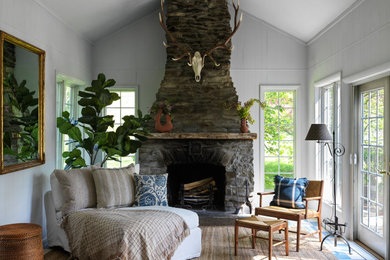 Exemple d'une grande salle de séjour nature ouverte avec un mur blanc, parquet clair, une cheminée standard, un manteau de cheminée en pierre et un sol bleu.